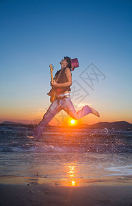日落时分，年轻人拿着吉他跳起来图片