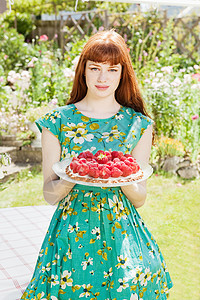 女人在花园里拿着草莓馅饼图片