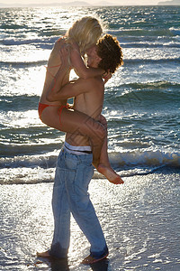 日落海滩上的年轻人亲吻图片