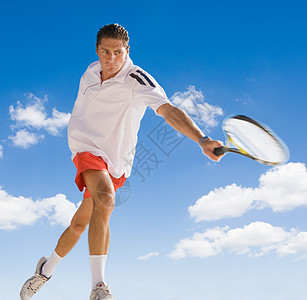 在蓝天下打网球的男子图片