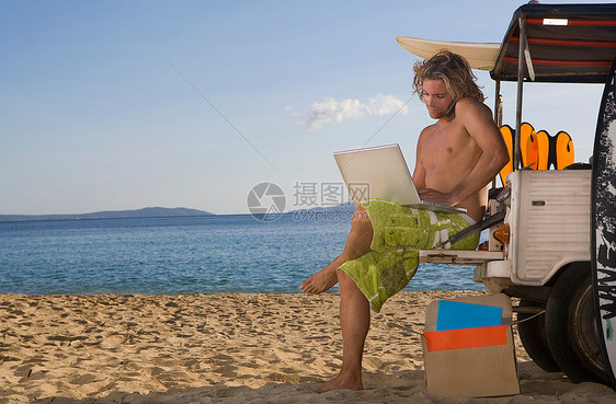 沙滩吉普车上的男人使用笔记本电脑图片