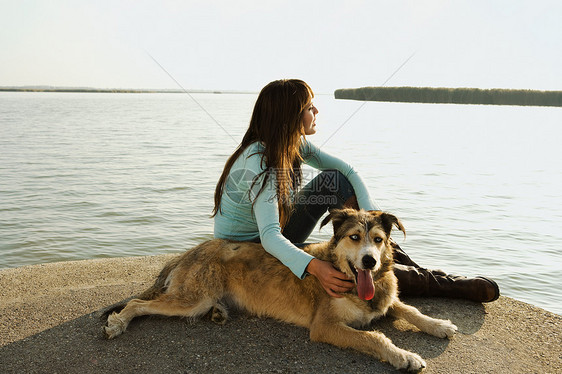 和狗一起坐在湖边的女人图片