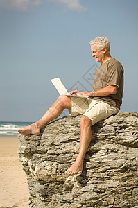 男人在海滩上用他的电脑图片