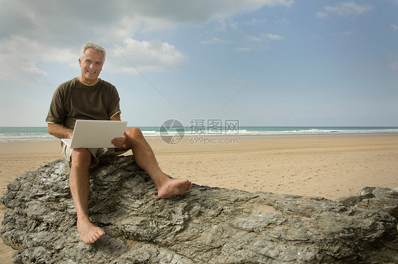 男人在海滩上用他的电脑图片