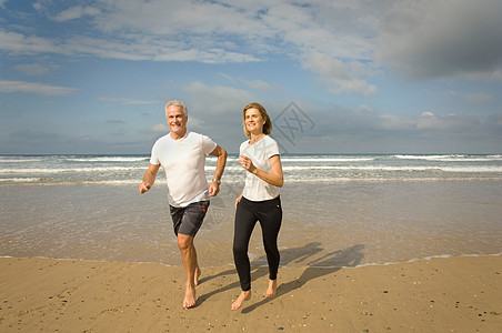 一对夫妇在海滩上奔跑图片