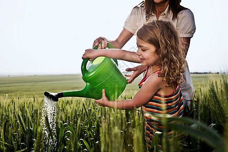 给麦田浇水的妇女和儿童背景图片