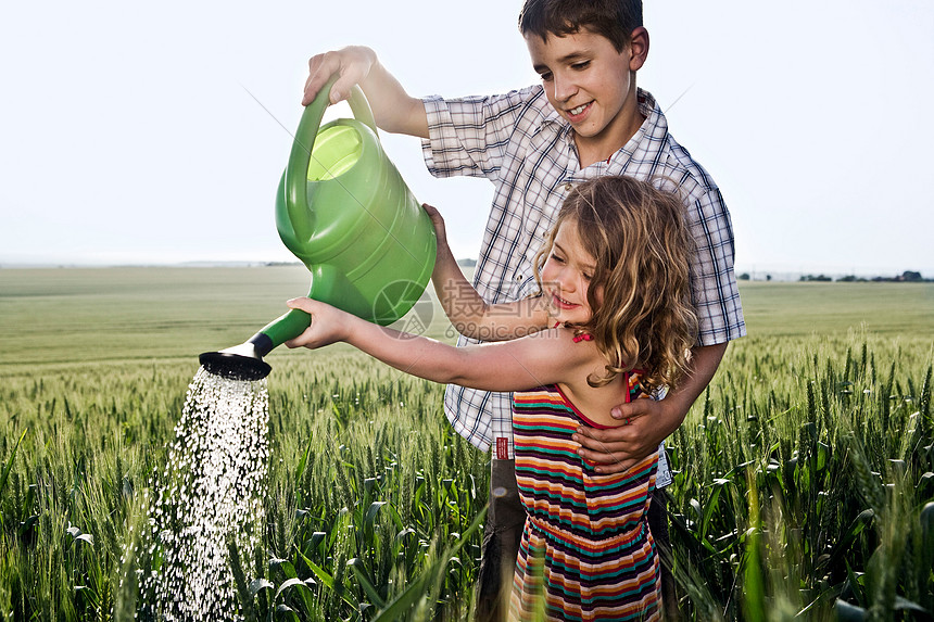 男孩帮女孩拿水壶浇水图片