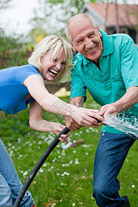 女孩和父亲在玩喷水的软管图片