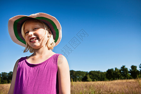 戴太阳帽的女孩在田野里微笑图片