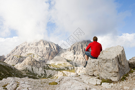 坐在岩石上看山峰的人图片