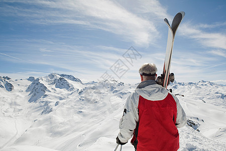 抱着滑雪板的成熟男人的后视图图片