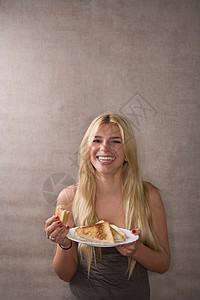 年轻女子微笑着吃三明治图片