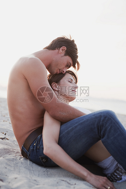坐在沙滩上拥抱的情侣图片