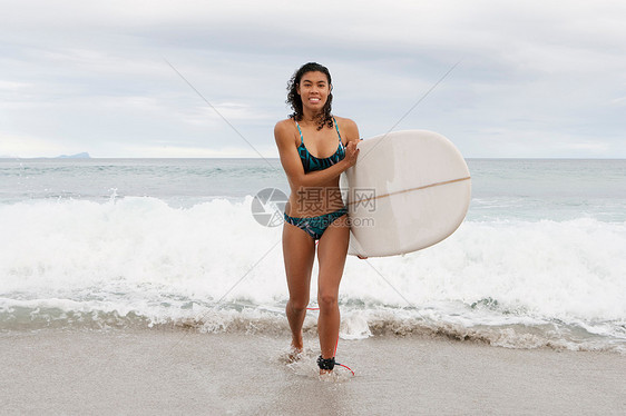 海滩上扛冲浪板的女人图片