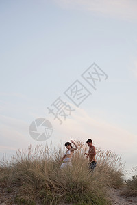 在海边芦苇丛中玩耍的一对夫妇图片