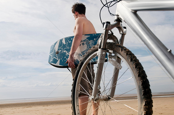 在海滩上骑自行车和冲浪板的男人图片