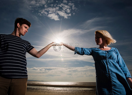 海滩上的一对夫妇手拿太阳图片