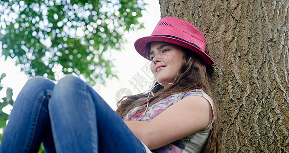 戴耳机的女孩靠在树上图片