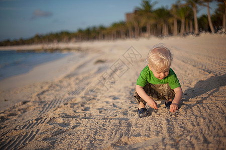 在海滩上玩沙子的小男孩图片