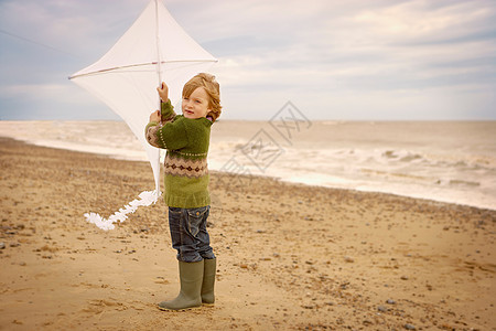 海滩上拿着风筝的小男孩图片
