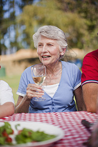 在野餐桌边喝酒的女人图片