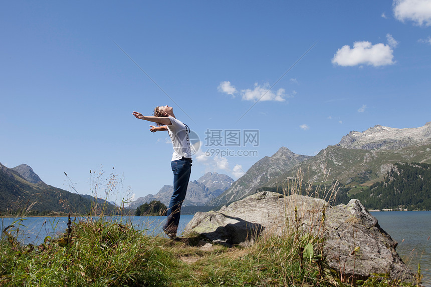 女人张开双臂站在湖边图片