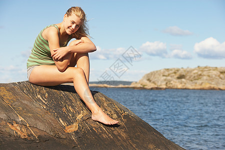在岩石上做瑜伽的年轻女子图片