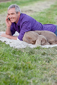 听电话带着狗的男人在草地上打电话背景