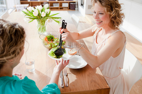 两个女人坐在桌上吃沙拉图片