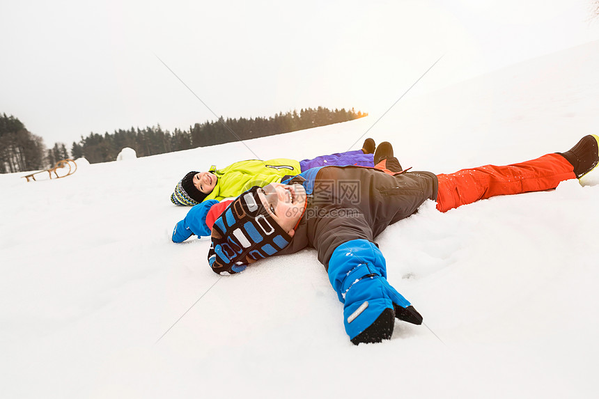 两个男孩躺在雪地里图片