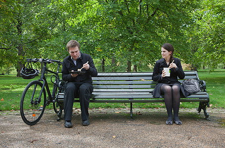 在公园长椅上吃午饭的女人和男人图片