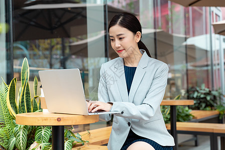 咖啡厅外景商务女性在咖啡厅用笔记本电脑办公背景