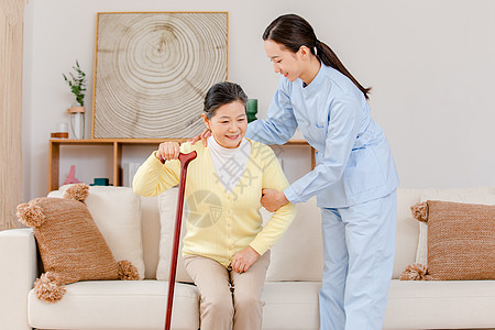 护工扶拄拐杖的老奶奶客厅散步背景图片