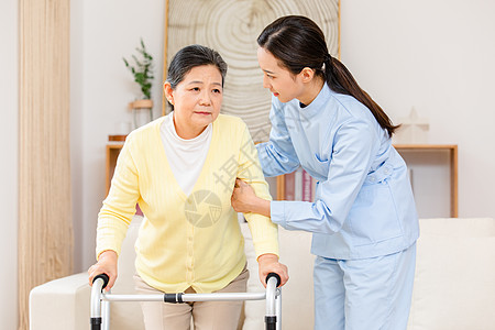 护工扶着使用健步器的老奶奶锻炼身体背景