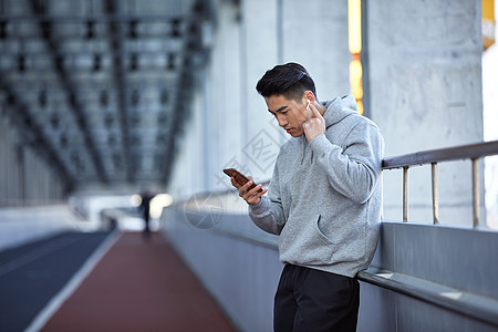 年轻运动男士户外使用蓝牙耳机通电话高清图片