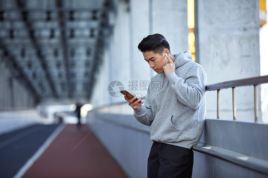 年轻运动男士户外使用蓝牙耳机通电话图片