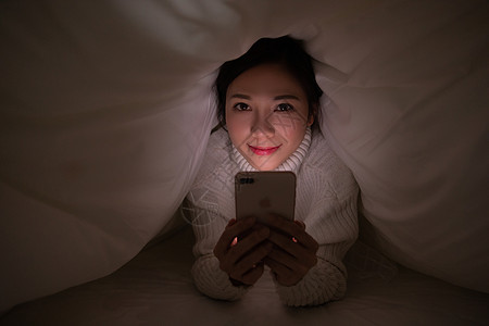 青年女性被窝熬夜玩手机图片素材