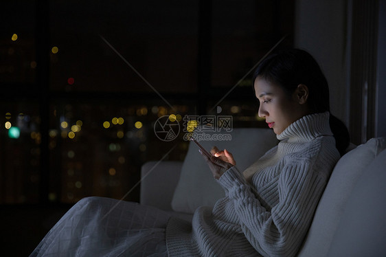 冬季青年女性夜晚玩手机图片