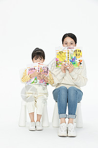 妈妈陪伴女儿坐在椅子上看童话故事书图片