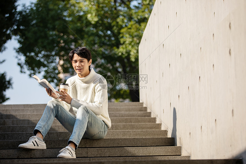 坐在楼梯上看书的青年男性
