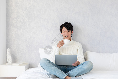 居家男性坐在床上喝咖啡图片
