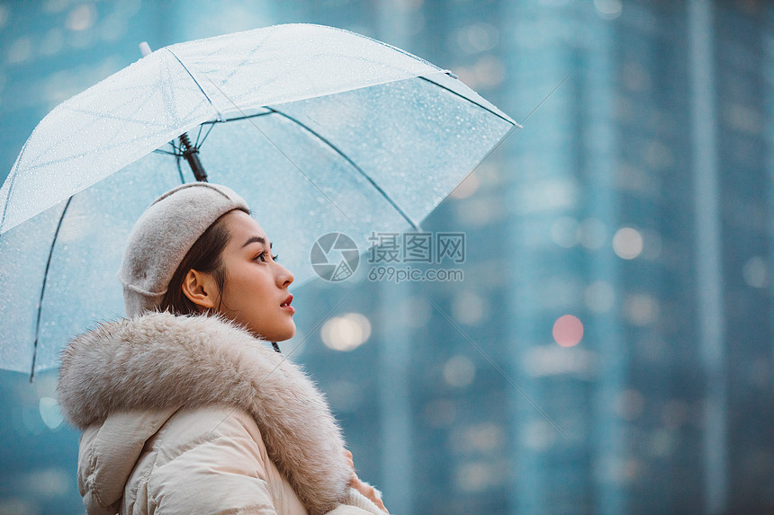 冬季女性户外下雨天撑伞看远方图片