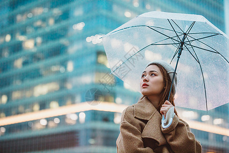 冬季女性户外下雨天撑伞看远方背景图片