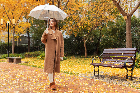 秋季雨天美女撑伞公园散步图片