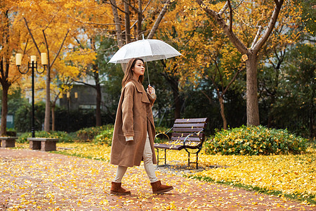 秋季雨天美女撑伞公园散步图片