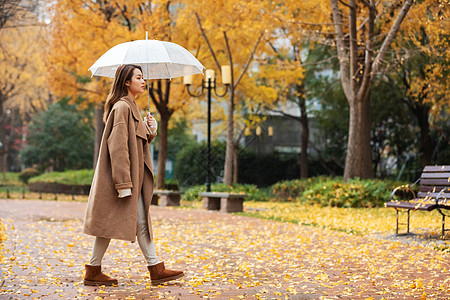 秋季雨天美女撑伞公园散步图片