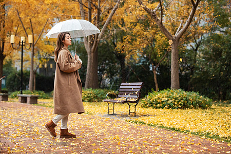 秋季雨天美女撑伞公园散步图片