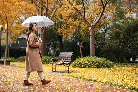 秋季雨天美女撑伞公园散步图片