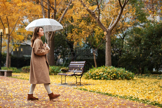 秋季雨天美女撑伞公园散步图片