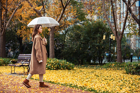 秋季雨天美女撑伞公园散步图片